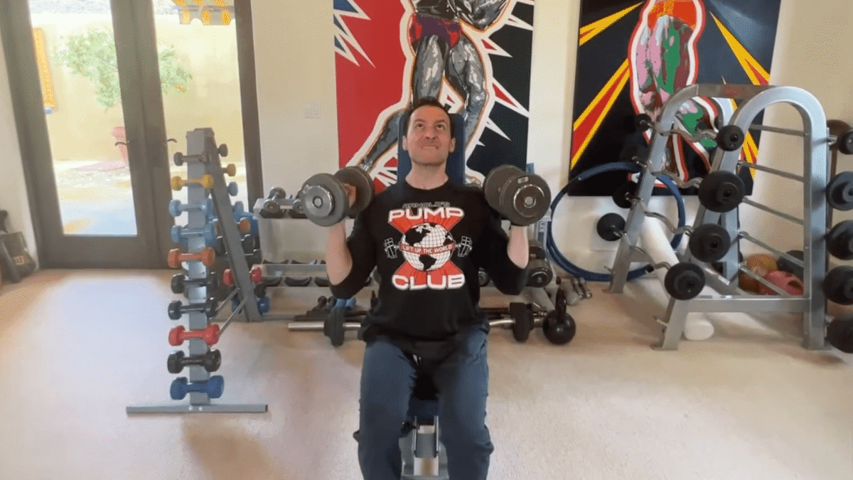 Man performing a seated dumbbell clean and press exercise
