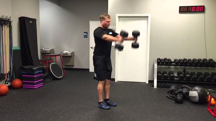 Man performing skier swings with two dumbbells