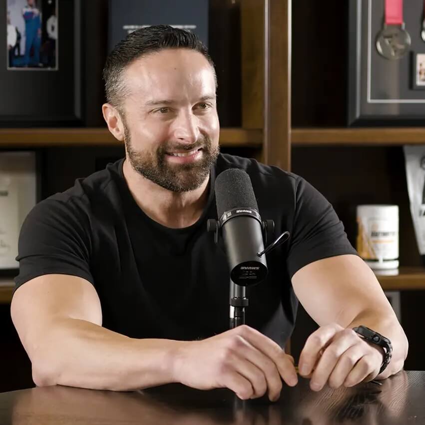 Photo of Dr. Layne Norton seated behind a table speaking into a microphone.